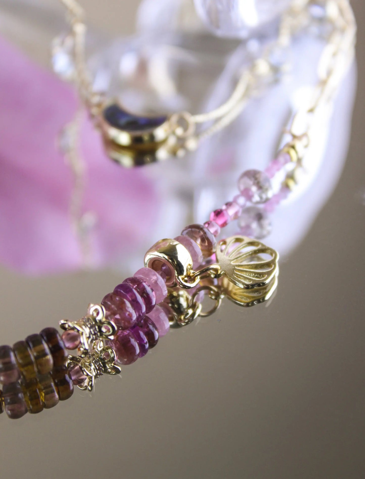 A close up picture of handmade tourmaline stone necklace with 14k gold plated decorations